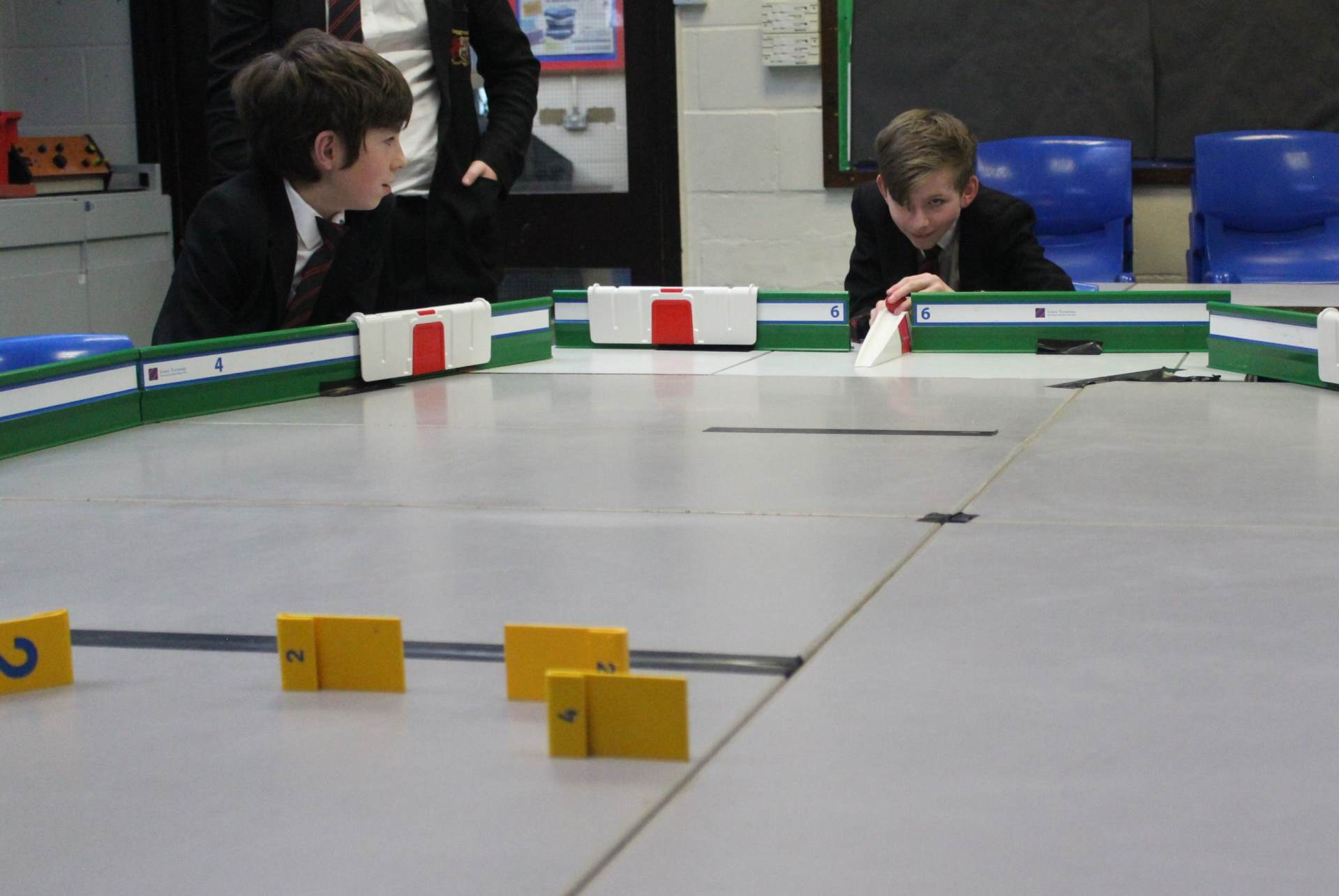 Students playing table top cricket and foccusing on bowling